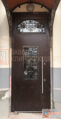 темно-коричневая входная дверь с арочным остеклением во фрамуге и отделкой порошковым напылением